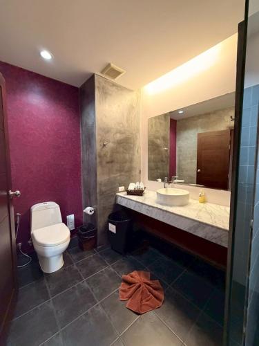 a bathroom with a toilet and a sink and a mirror at Le Patta Resort & Hotel Chiang Rai in Chiang Rai