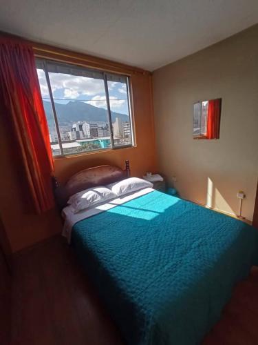a bedroom with a blue bed and a window at Hostal home 3 in Quito