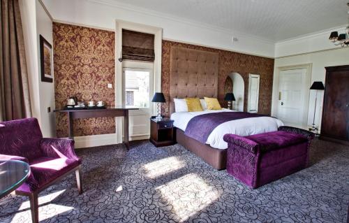 a bedroom with a bed and two chairs and a table at Pontlands Park Hotel in Chelmsford
