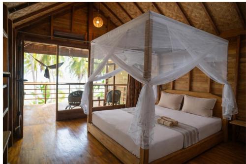 a bedroom with a bed with a canopy at BaraCoco Bungalows in Bira