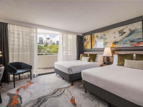 a hotel room with two beds and a window at Mercure Brisbane Spring Hill in Brisbane