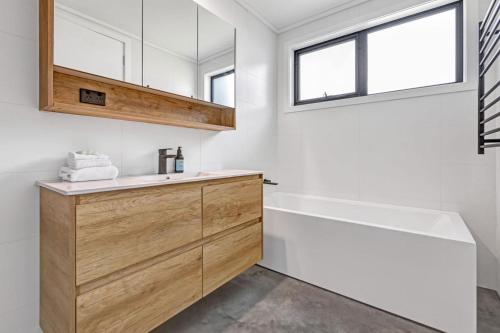 a bathroom with a sink and a bath tub and a window at Sheoak in Paynesville