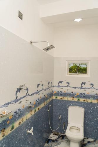 a bathroom with a toilet and a wall with animals painted on it at Risha villa in Trincomalee