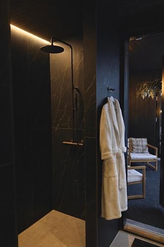 a bathroom with a shower with a white robe at Villa Blackreindeer in Kolari