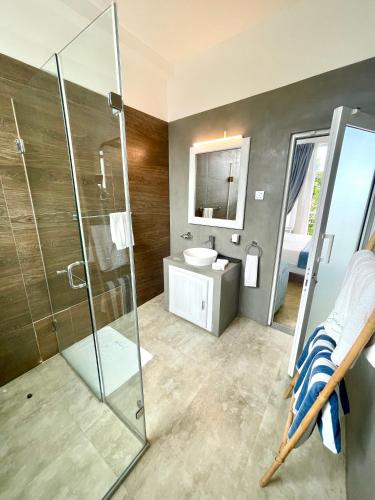 a bathroom with a glass shower and a sink at Baia Dikwella in Batigama
