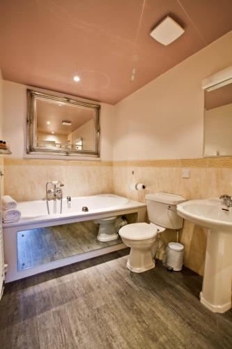 a bathroom with a tub and a toilet and a sink at Pontlands Park Hotel in Chelmsford