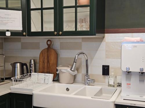 a kitchen counter with a sink and a kitchenilit at Miracle Suite House 1 in Incheon