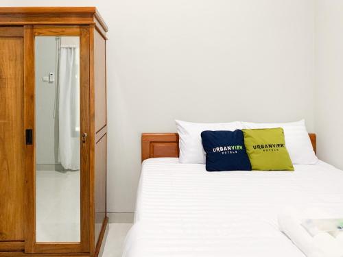 a bedroom with a bed with two pillows on it at Urbanview Hotel The Corner Pandowo in Ngaglik
