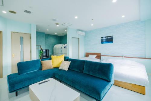 a living room with a blue couch and a bed at Sea Side Gaia Resort HOTEL シーサイドガイアリゾートホテル in Sendai