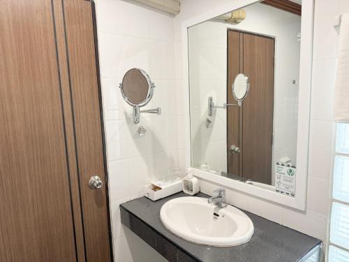 a bathroom with a sink and a mirror at Sakol Hotel in Hat Yai