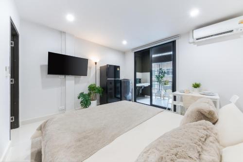 a white bedroom with a large bed and a flat screen tv at Petchaburi31 Platinum Suite Home in Bangkok