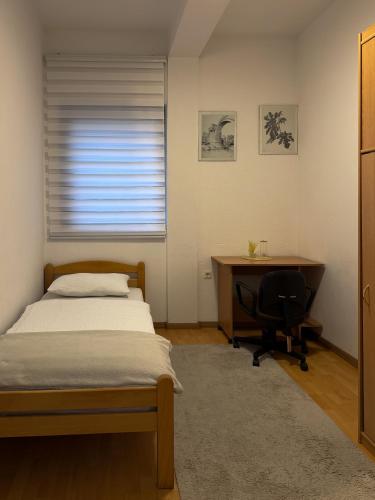 ein Schlafzimmer mit Bett, Schreibtisch und Fenster in der Unterkunft Riaho Apartment in Mostar