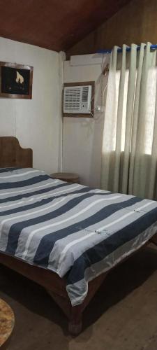 a bed with a blue and white striped comforter in a bedroom at Bebot's Breakfast #01 in Daanbantayan