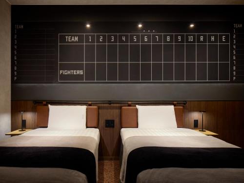 two beds in a room with a chalkboard on the wall at tower eleven hotel in Kitahiroshima