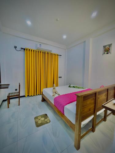 a bedroom with a bed and a yellow curtain at Akarsha Residence - Near Airport in Negombo