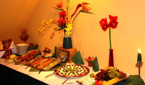 a table with food and flowers on a table at Hotel-Pension Grüne Linde in Delitzsch