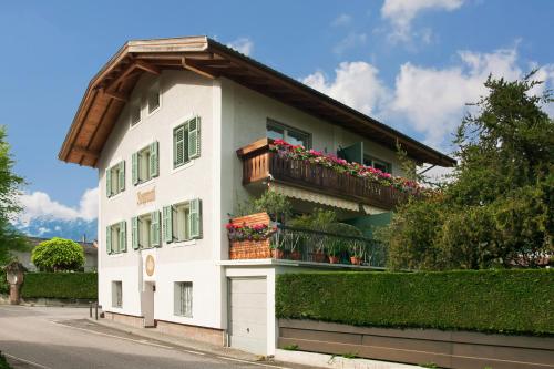 a white building with a balcony with flowers on it at Neuprantl Apartments in Lana