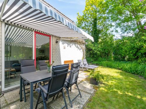 a patio with a table and chairs in a yard at Holiday Home near Dutch Beach with Pool in Sint Maartensvlotbrug