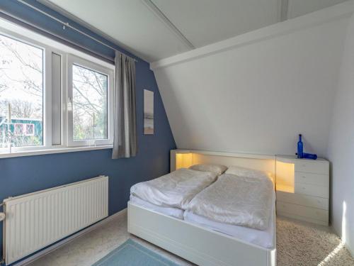 a bedroom with a white bed and two windows at Holiday Home near Dutch Beach with Pool in Sint Maartensvlotbrug