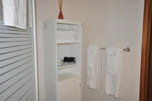 a bathroom with white towels and a black cat on a shelf at Garden House in Courtenay