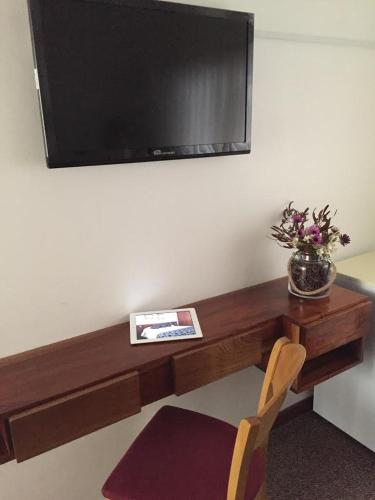 a wooden desk with a television on a wall at Hotel Morales in San Clemente del Tuyú