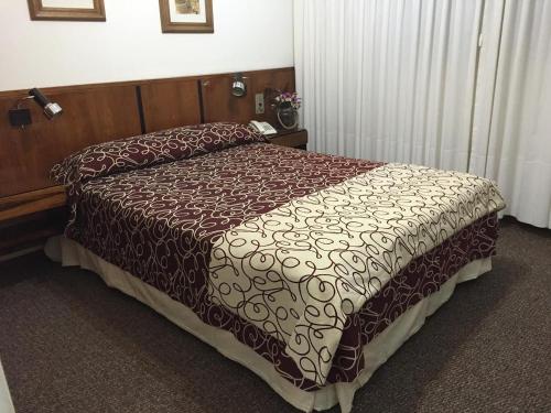 a bed in a hotel room with a brown comforter at Hotel Morales in San Clemente del Tuyú
