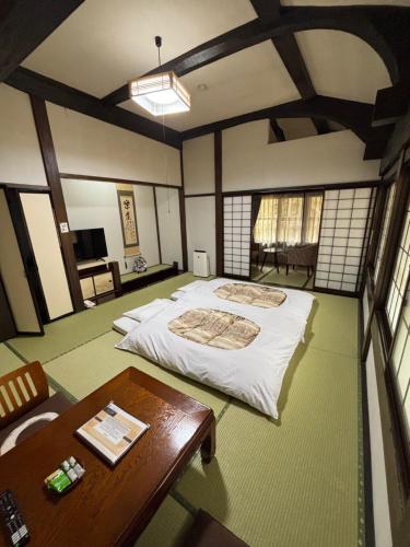 a bedroom with a large bed and a table at Ryokan Murayama in Takayama