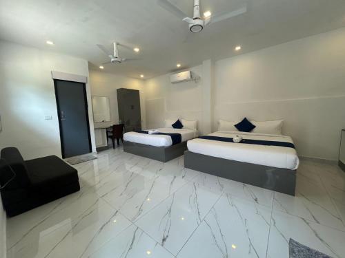a hotel room with two beds and a chair at Hotel unity Park in Pondicherry