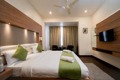a bedroom with a large bed with a flat screen tv at The Altruist Katra Hotel in Katra