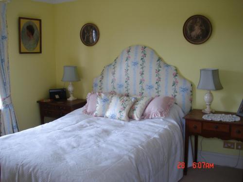 a bedroom with a white bed with a headboard and two tables at Petercott in Shepton Mallet