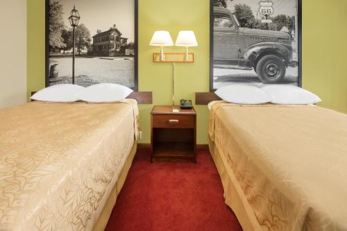 a hotel room with two beds and a picture of a car at Super 8 by Wyndham Normal Bloomington in Bloomington