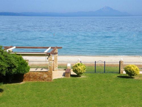 a view of a beach with a fence and the ocean at Villa Nefeli - Akti Salonikiou A in Agios Nikolaos