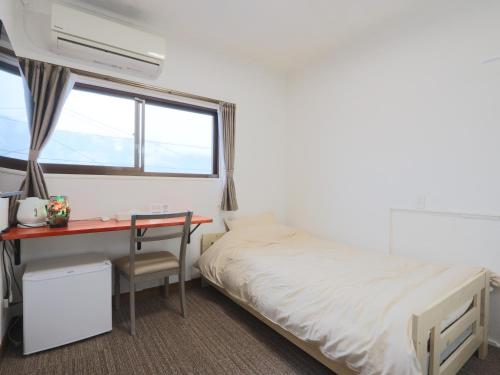 a bedroom with a bed and a desk and a window at 港の魚宿 おおそね in Owase