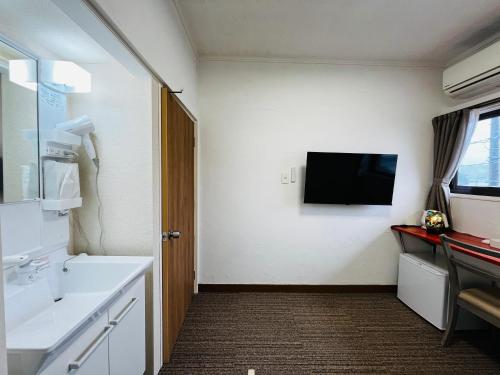 a bathroom with a sink and a tv on the wall at 港の魚宿 おおそね in Owase