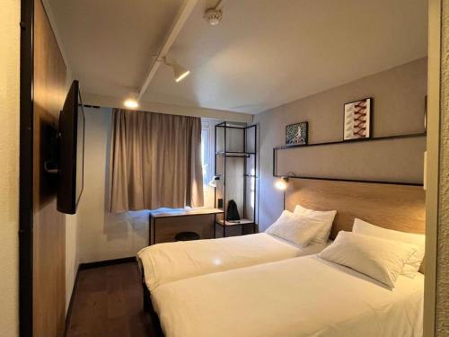 a hotel room with two beds and a television at ibis Toulouse Aeroport in Blagnac