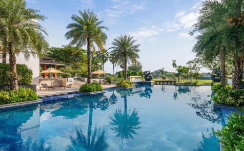 an infinity pool at a resort with palm trees at Hilton Bangkok Suvarnabhumi Golf Resort & Spa in Lat Krabang