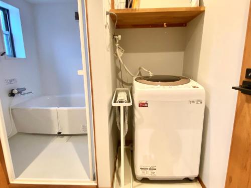 a small bathroom with a washing machine and a tub at SUMITSUGU HOUSE Atelier in Kumamoto