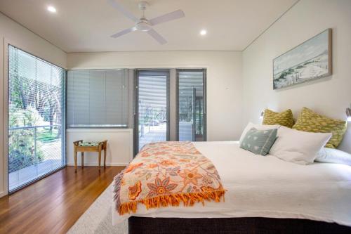 a bedroom with a large bed with a ceiling fan at The Banksia's in Tea Gardens