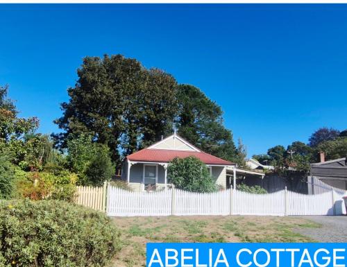 a house with a white fence and a sign that says beta cottage at Daylesford A Very Quiet ABELIA COTTAGE BOTANICAL COTTAGE 10 min walk town in Daylesford
