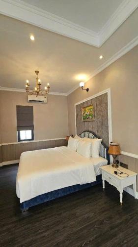 a bedroom with a large white bed and a table at Vườn vua thanh thuỷ in Ðồng Phú