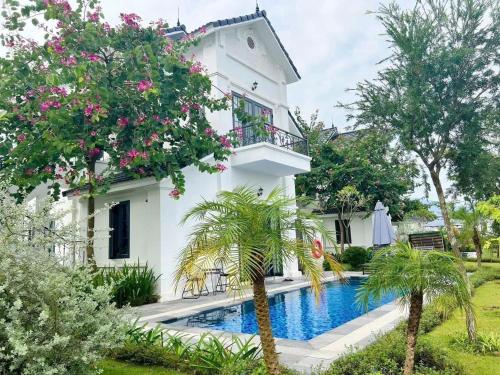 a white house with a swimming pool and trees at Vườn vua thanh thuỷ in Ðồng Phú