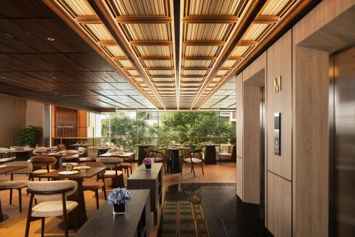 a restaurant with wooden ceilings and tables and chairs at The Auberg Collection Hotel in Ho Chi Minh City