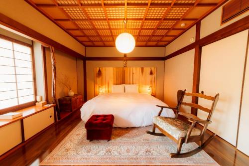 a bedroom with a bed and a chair in it at めぐり宿 庵結 in Shimonoseki