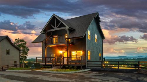 a large house with a sunset in the background at Jolene- Cabin Goals, Best Location, Pool & Hot Tub, Dogs! in Sevierville