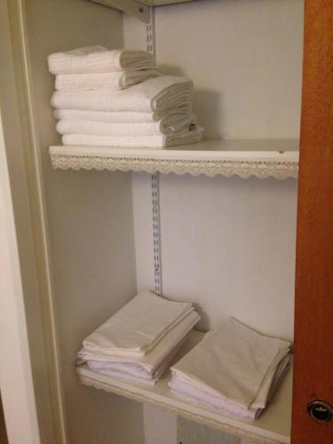 un armario con toallas blancas en un estante en A la meseta en Puerto Madryn