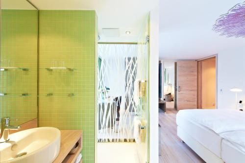 a bathroom with a sink and a bedroom with green tiles at Schwanen Boutique Hotel & Restaurant Metzingen in Metzingen