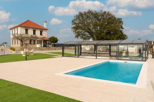 a swimming pool in front of a house with a gazebo at O Paraíso do Sobreiro - Country House in Travanca de Lagos
