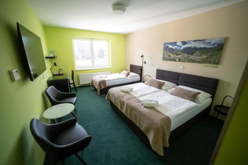a hotel room with two beds and a table and chairs at Garni hotel Svitavy in Svitavy
