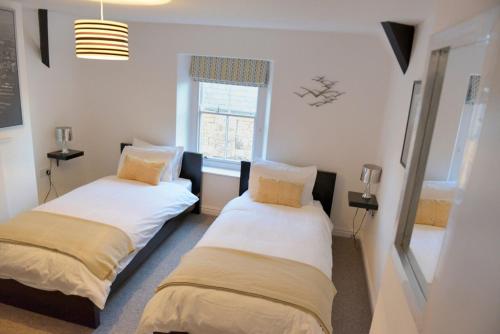 two beds in a room with a window at The Loft at Venga in Portishead