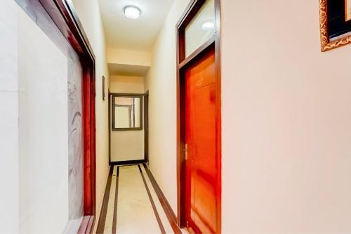 a hallway with a red door and a tile floor at Hotel O Le Regent in Gurgaon